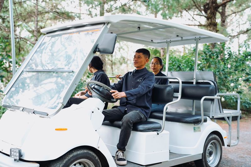 Nhân viên GIA AN lái xe buggy trắng đón khách dưới rừng thông